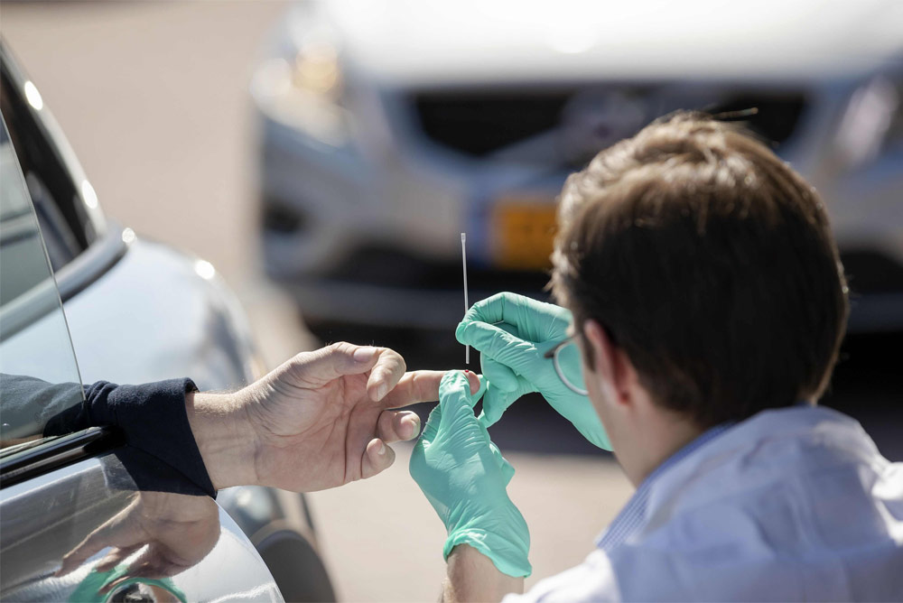 A medical staff takes samples from a vehicle occupant to test for the COVID-19 infection