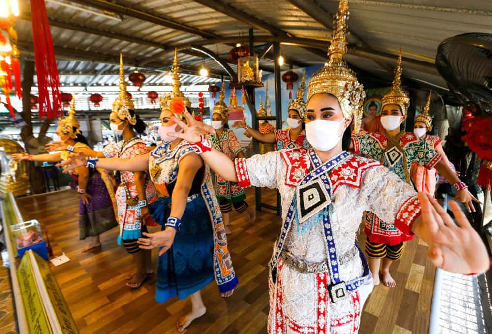 Performers wearing protective face shields perform at the Erawan Shrine, Bangkok, Thailand