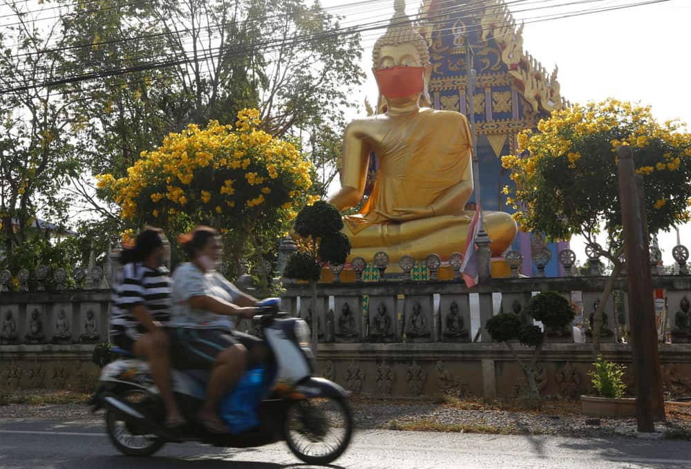 A Buddha statue decorated with a face mask on the outskirts of Bangkok